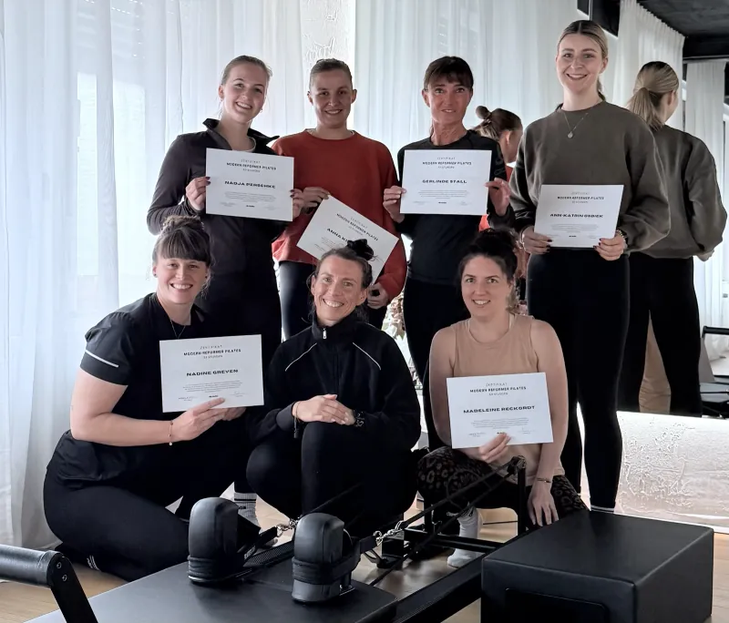 Gruppenfoto: Teilnehmerinnen der Reformer Pilates Ausbildung zeigen ihre Zertifikate nach der Prüfung bei olia